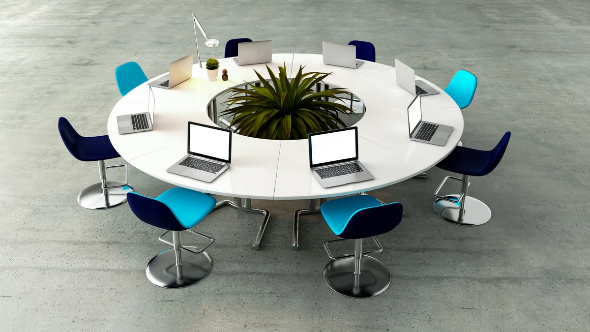 Sala de reunion con una mesa redonda y sillas vacias, a la luz de la tarde, lista para el encuentro.